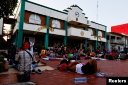 Los migrantes que viajan en una caravana descansan fuera del palacio municipal antes de continuar su viaje a través de México, en un intento de llegar a la frontera con Estados Unidos, en Villa Comaltitlán, México, el 26 de diciembre de 2023. REUTERS/José Torres