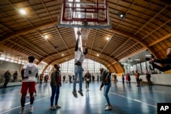 El atleta cubano Yoao Illa, bronce en los 400 metros con vallas en los Juegos Panamericanos (centro), juega baloncesto con otros atletas cubanos que abandonaron la delegación cubana. AP/Esteban Félix