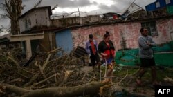 Residentes del barrio de Regla caminan sobre los escombros en busca de sus pertenencias. 