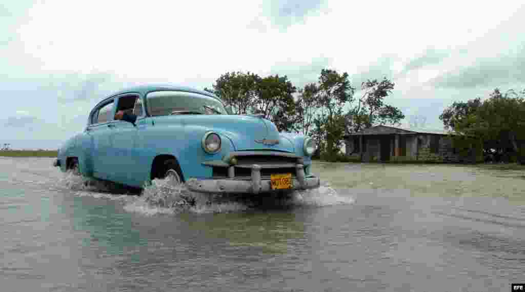 Un auto pasa sobre las aguas desboradas del rio La Rosita, Matanzas (Cuba).