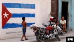 Un niño pasa junto a una pintura de la bandera cubana en una pared, en La Habana, Cuba.