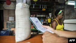 Un hombre espera comida en una tienda mientras sostiene una "libreta", una tarjeta de racionamiento que desde 1963 ha permitido a los cubanos comprar alimentos básicos.