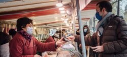 Personas con mascarillas contra el COVID-19 en un mercado de París, Francia.