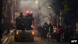 Bolivianos saludan en una calle de La Paz la noche del domingo a un vehículo de la policía que patrulla la zona (Foto: Ronaldo Schemidt/AFP).