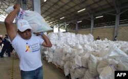 Un voluntario carga una bolsa con ayuda enviada por EEUU a los venezolanos, en el centro de acopio de Cúcuta.