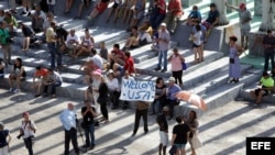 Un hombre muestra un cartel junto a decenas de curiosos y periodistas frente a la embajada de Estados Unidos en Cuba.