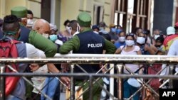 Policías controlando la población en una cola para conseguir alimentos.