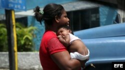 Una mujer carga a su pequeño hijo en La Habana. Archivo.