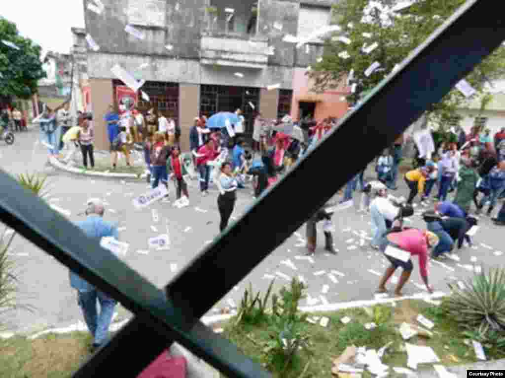 Miembros de las BRR recogen los volantes y ejemplares de la Declaración Universal de los Derechos Humanos que lanzaron hacia la calle las Damas de Blanco. Foto cortesía Ángel Moya.