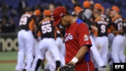 El jugador cubano Jose Abreu pasa delante del equipo holandés, que se encuentra celebrando su victoria tras imponerse a Cuba en el Clásico Mundial de Béisbol disputado en el estadio Tokyo (Japón). 