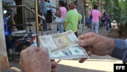 Un hombre muestra un peso convertible cubano y un dólar estadounidense frente a una oficina de la Western Union en La Habana. (Archivo)