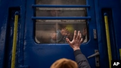 Un hombre llamado Stanislav se despide de su hijo David, de 2 años, y de su esposa Anna, luego de que abordaran un tren que los llevará a Lviv, Ucrania, el jueves 3 de marzo de 2022. (Foto AP/Emilio Morenatti).