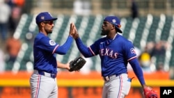 Marcus Semien, izquierda, y Adolis García, de los Rangers de Texas, celebran después de un partido de béisbol contra los Tigres de Detroit el 18 de abril de 2024, en Detroit. (AP Foto/Paul Sancya