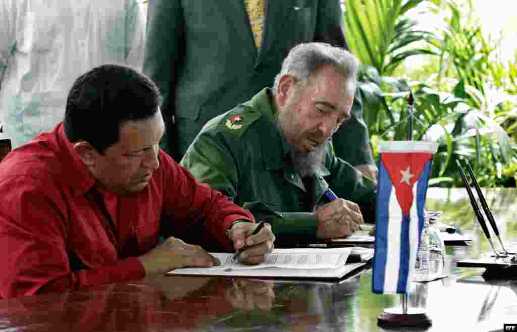 Hugo Chávez y Fidel Castro suscribiendo un convenio.