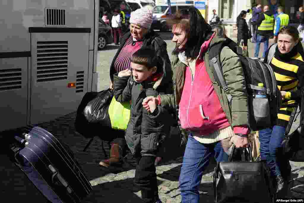 Refugiados ucranianos acompañados de niños se suben a un tren en una estación en Przemysl, Polonia. Foto: AP/Sergei Grits.