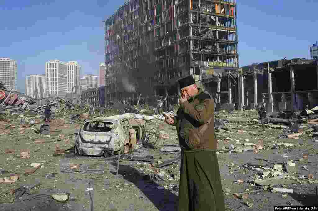 Un sacerdote reza en las ruinas de un centro comercial destrozado después de un bombardeo ruso en Kyiv, Ucrania. Foto: AP/Efrem Lukatsky.