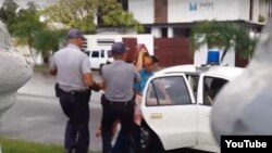 Un agente de la Seguridad del Estado y dos policías arrestan a la activista Ailer González.