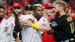 Yasiel Puig (66) de los Rojos de Cincinnati es contenido por Colin Moran de los Piratas de Pittsburgh, el martes 30 de julio de 2019. (AP Foto/John Minchillo)