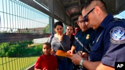 Agentes de Frontera procesan a una familia cubana en el Puente Internacional de Nuevo Laredo, Texas, el 10 de julio de 2019. (Foto AP /Salvador Gonzalez)