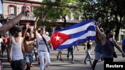 Manifestantes sostienen una bandera cubana durante las protestas del 11 de julio, en La Habana, Cuba. (REUTERS/Alexandre Meneghini).