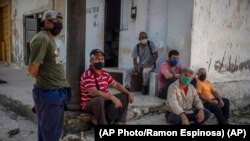 Trabajadores con sus máscaras esperan a las afueras de un central azucarero en Madruga, Cuba. (AP/Ramón Espinosa)