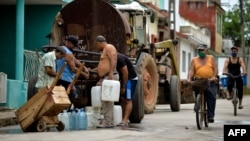 Vecinos recogen agua de una pipa la mañana del martes en un barrio de San Antonio de los Baños, en la provincia de Artemisa (Yamil Lage/AFP).