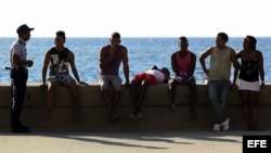 Un policía junto a varios jóvenes en el malecón de La Habana (Cuba). Foto Archivo.