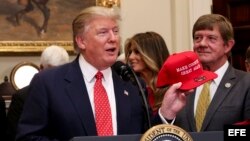 El presidente Donald Trump sostiene su gorra de campaña en el salón Roosvelt de la Casa Blanca.