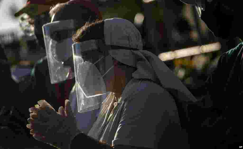 Seguidores de San Lázaro, con máscaras, en medio de la pandemia de coronavirus, rezan durante la peregrinación al santuario del santo para su fiesta anual, en el barrio El Rincón de Santiago de Las Vegas. (AP Photo/Ramon Espinosa)