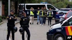 Policías montan guardia mientras otros agentes con chalecos amarillos caminan hacia atrás junto a la embajada de Ucrania en Madrid, el miércoles 30 de noviembre de 2022. (AP Foto/Paul White)