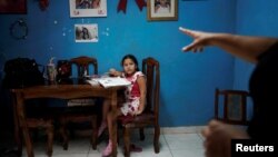 Liz Mariam recibe instrucciones de su mamá para hacer las clases a distancia. COVID-19. REUTERS/Alexandre Meneghini