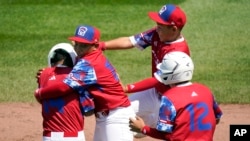 Luis Gurriel (14) abrazado por sus compañeros de equipo Didier Castillo (15), Edgar Torrez y Liusban Sanchez (12) después de que impulsó la carrera final de su victoria 11-1 contra Australia en South Williamsport, Pensilvania, el sábado 19 de agosto de 2023. Foto AP/Tom E. Puskar